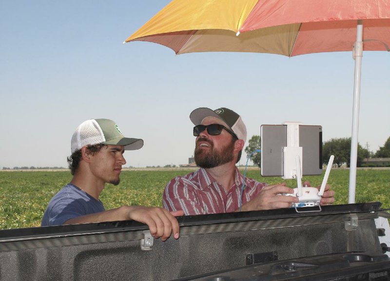 Intern Christian Cambrelan (left) watches as Bowles Farming Co. vice president of technology Danny Royer pilots a drone over a tomato field near Los Banos, Calif.