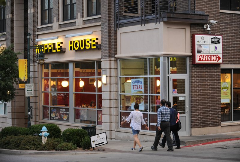 Pedestrians walk Tuesday past a Waffle House restaurant on West Dickson Street in Fayetteville. Once the home to only locally owned businesses, national chain restaurants have begun moving into the city’s entertainment district.