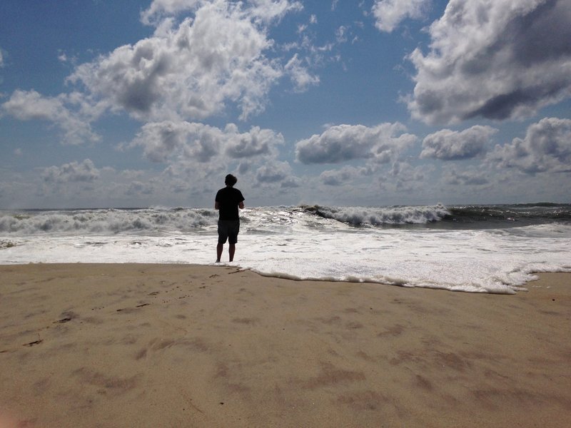 A beachgoer stands at the edge of the water, Sunday, Sept. 4, 2016, in Bridgehampton, N.Y., on the southeastern shore of Long Island, where the effects of storm system Hermine could be seen in the rough surf and a ban on swimming. 