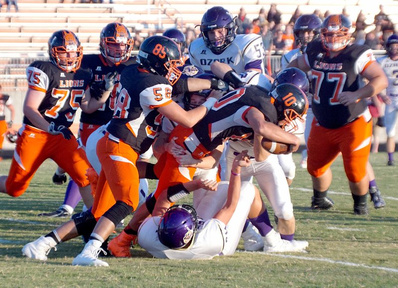 Photo by Randy Moll Austin O&#8217;Brien, Gravette junior, backed by Dalton Bass (No. 58) struggles for another yard while Ozark defenders pull him down during play in Lion Stadium against the visiting Hillbillies from Ozark on Friday, Sept. 2, 2016.