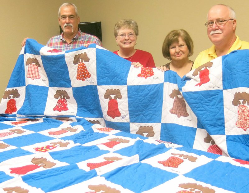 Steve Mitchael, left, chairman of the Gravette Historical Museum Commission, helps Geraldine Carpenter, museum commissioner Lavon Stark and Centerton Mayor Bill Edwards display a Liberty Bell quilt at Centerton City Hall. The quilt was made and raffled to raise funds for the first Centerton Day in 1976. Mitchael and Stark presented the quilt to Carpenter last week. She had worked on the quilt and her name is listed on one of the blocks.