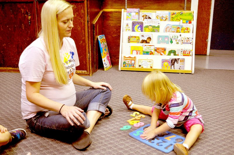 RACHEL DICKERSON/MCDONALD COUNTY PRESS Jennifer Harris, left, director of We Care for Wee Folks daycare in Noel, helps Olivia Buckridge, 2, with a puzzle.