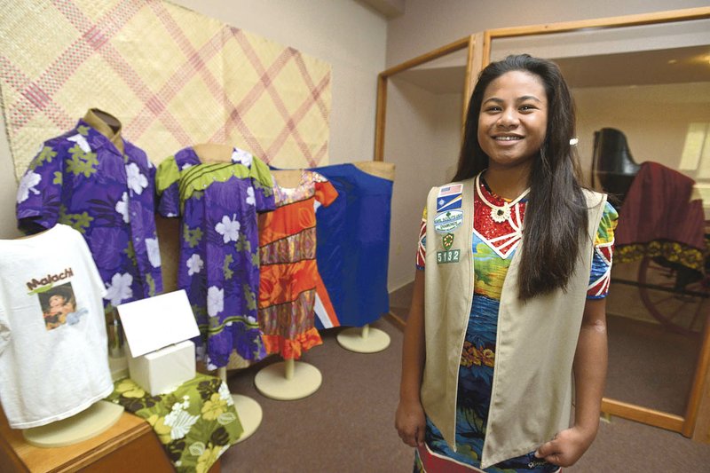 Rona Masha, 14, of Springdale, a Cadette Girl Scout with Troop 5132, poses with dresses on display at the Shiloh Museum of Ozark History in Springdale. Rona served as guest curator for the museum’s exhibit “Marshallese Celebrations: From the Atolls to the Ozarks.”