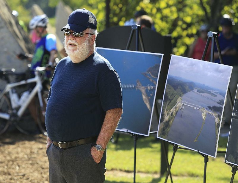 Former Pulaski County Judge Buddy Villines stands next to photos of the Big Dam Bridge on Thursday morning during a ceremony to celebrate the 10th anniversary of the span. Villines was in office during the planning and construction of the pedestrian bridge, a key link in the Arkansas River Trail. 