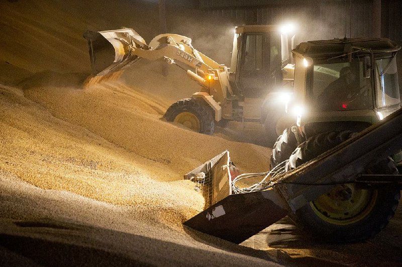 A wheel loader (left) moves corn inside a storage facility at Michlig Grain in Sheffield, Ill., in March. A third-straight bumper harvest across the U.S. has created a grain storage crunch.