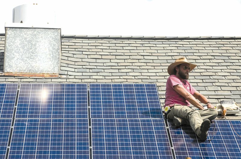 Joe Rice works on installing the final solar panel on the roof of the youth building at St. Mark’s Episcopal Church in Little Rock. The 10 panels are expected to produce about 313 kilowatt hours of electricity each month. 