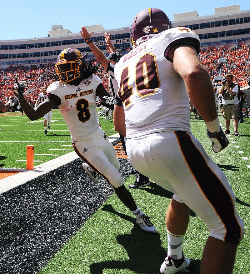 An official signals a touchdown as Central Michigan wide receiver Corey Willis (8) celebrates with teammate Joe Bacci after scoring the winning touchdown after time had expired Saturday in a 30-27 victory over No. 22 Oklahoma State at Boone Pickens Stadium in Stillwater, Okla. Article, 