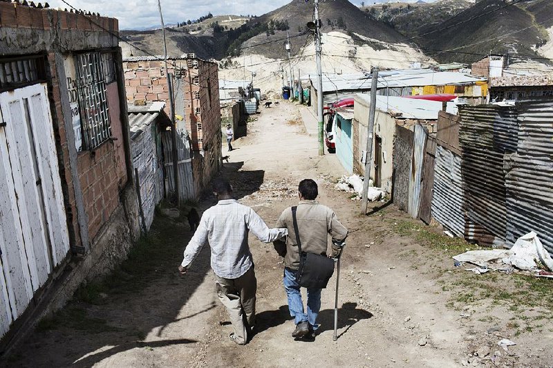 Isaac Valencia (left) helps Ruben Dario Quevedo down a steep hill in the Soacha slum outside Bogota, Colombia. Violence in the countryside displaced both men. Valencia would like to eventually return to his farm, but Quevedo said he has no desire to go back.