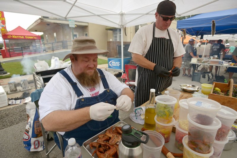 James Worley (left) and Brett Atkinson, the Limb Bacon Allstars from Kansas City, Mo., prepare their squirrel dishes for the competition Saturday during the annual World Championship Squirrel Cookoff in downtown Bentonville.