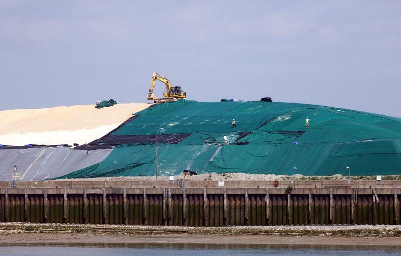 An excavator and employees stand on a mound of unrefined cane sugar at the Tate & Lyle Plc Thames Refinery in London in this May file photo. A report published Monday said sugar-industrygroup- funded medical research questioned sugar’s role in heart disease.