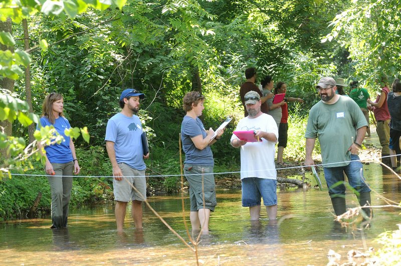 Sabrina Bowman with Beaver Water District (left) helps Stream Smart volunteers, including Heather Harvey (third from left) measure the flow rate of Prairie Creek in July.