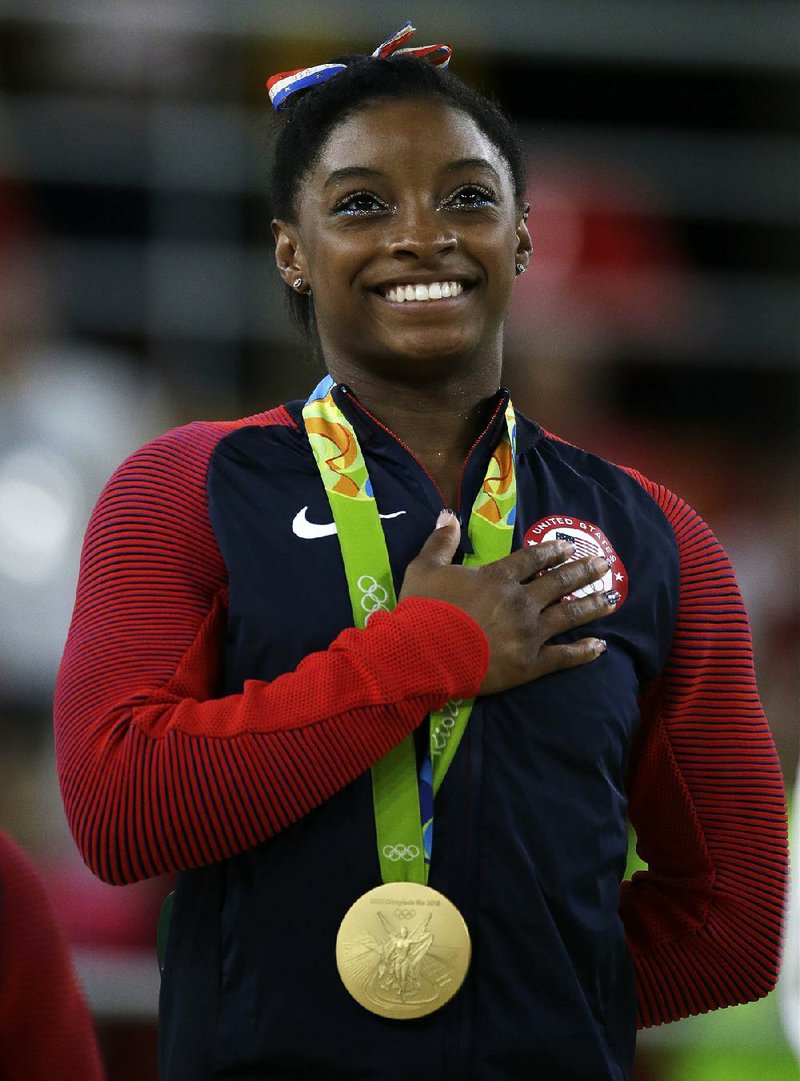In this Aug. 16, 2016, file photo, United States' Simone Biles stands during the national anthem after winning the gold medal in the women's floor exercise at the 2016 Summer Olympics in Rio de Janeiro, Brazil. 