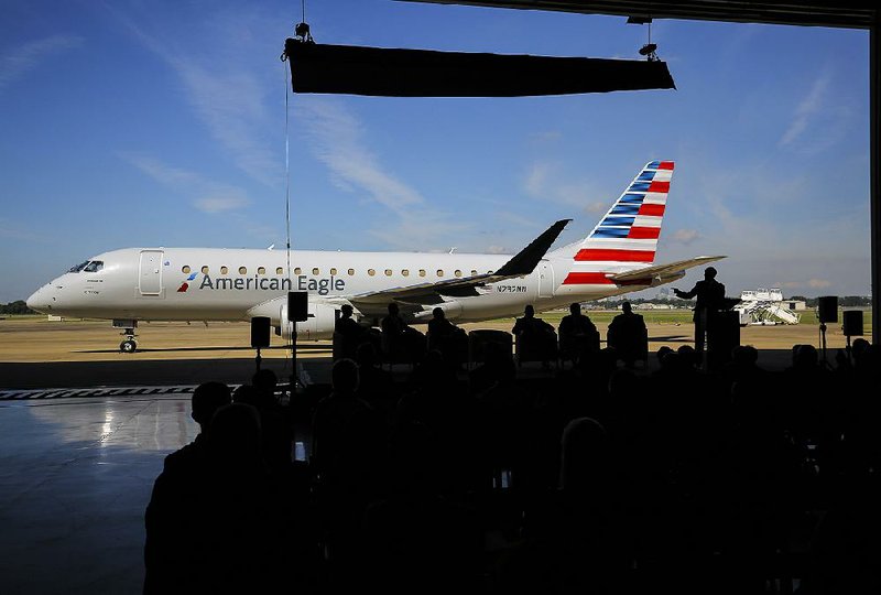 Gov. Asa Hutchinson (right) speaks Tuesday after unveiling an American Airlines Embraer 175 jet. The 76-seat jets, which fly regional routes, will be maintained by Envoy Air at Bill and Hillary Clinton National Airport/Adams Field in Little Rock after modifications to a hangar. 
