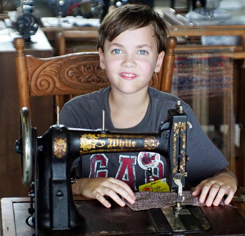 Photo by Randy Moll Caleb Brummitt, 10, tries running an antique White sewing machine in the antique home furnishings building at the Tired Iron of the Ozarks fall show on Friday, Sept. 9, 2016, in Gentry.