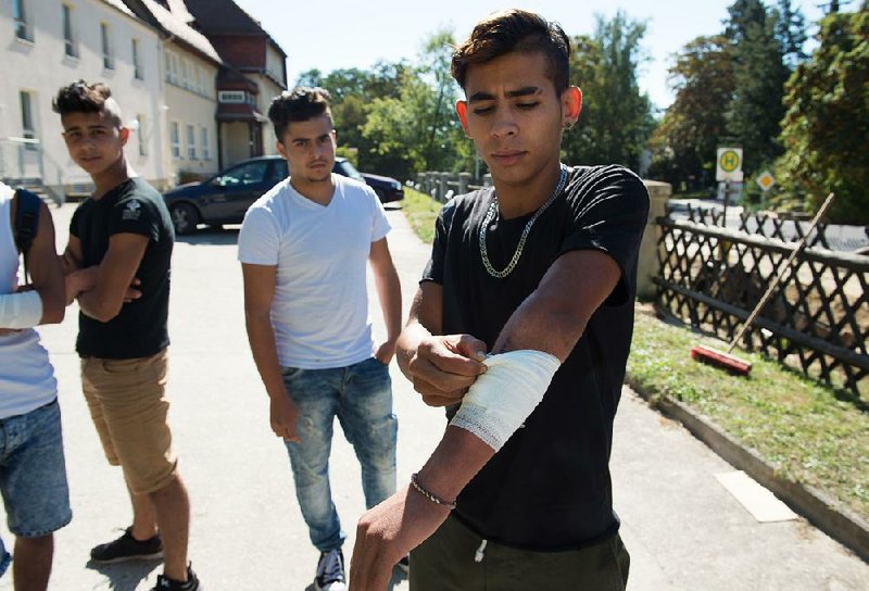 Mehdi (right) from Morocco shows an injury on his arm Thursday in Bautzen, Germany, that he says he suffered during riots.