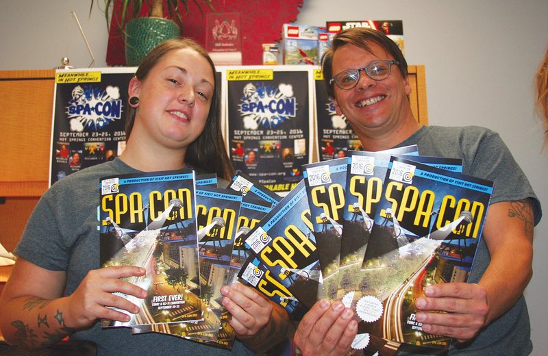 Erin Baber, public relations coordinator for Garland County Library, and Bill Solleder, special events manager for Visit Hot Springs, pose with a handful of Spa-Con programs. The inaugural comic and sci-fi convention, will run Friday through Sept. 25.