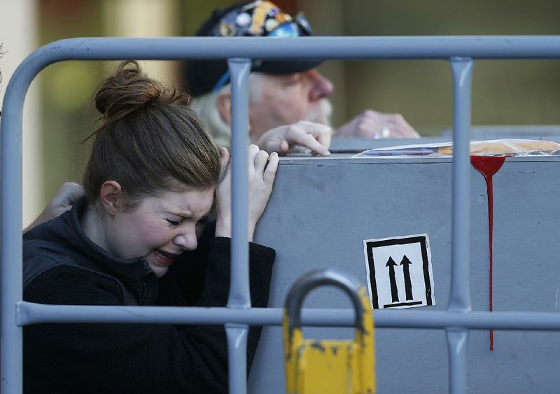 Katie Shirley and her father, Russ Shirley, grieve Friday as the container bearing the remains of Russ’ son Levi arrives in Denver along with the remains of Jordan MacTaggart.