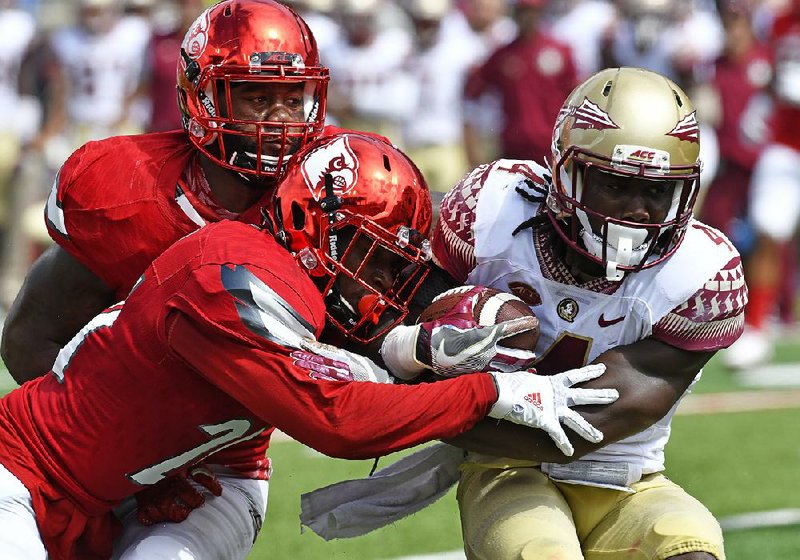 Florida State running back Dalvin Cook (4) is tackled by Louisville cornerback Zykiesis Cannon (24) during the third quarter of an NCAA college football game, Saturday, Sep. 17, 2016 in Louisville Ky. Louisville won 63-20. (AP Photo/Timothy D. Easley)