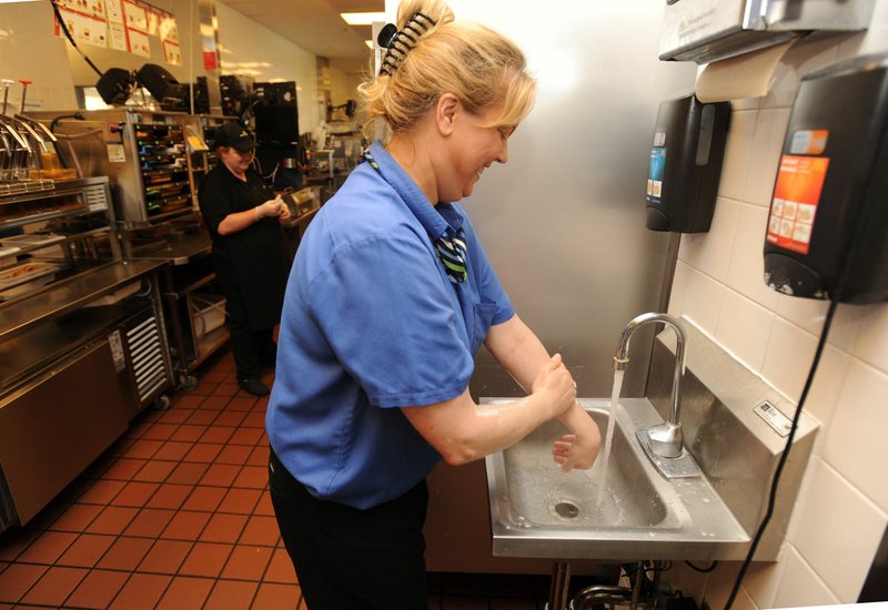 Michelle Karnes, a manager for the McDonald’s restaurant at 4762 Elm Springs Road in Springdale, washes her hands Thursday in a sink made for that purpose while working at the restaurant. Northwest Arkansas’ McDonald’s restaurants have trained all of its managers in food preparation and storage techniques.