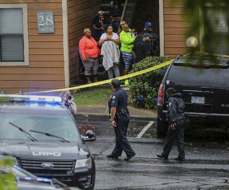 Residents at the Shadow Lake Apartments at 13111 W. Markham St. watch as Little Rock police investigate the scene of a homicide Sunday in Little Rock.