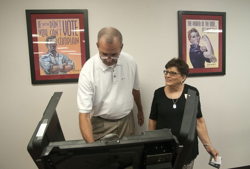 Mike Frost of Bentonville gets help at an electronic voting machine from ballot judge Nancy McLoud at the Benton County Courthouse on Monday. Polling places in Benton County will be open today for the annual school board election.