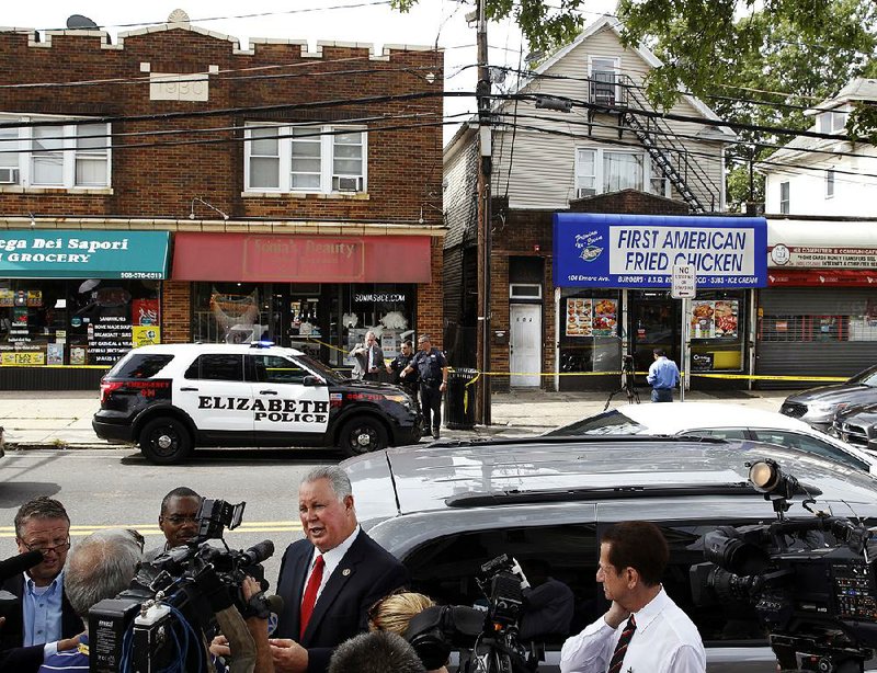 U.S. Rep. Albio Sires (center), D-N.J., answers a question across the street from the First American Fried Chicken restaurant Tuesday in Elizabeth, N.J.