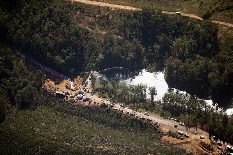 Workers spray water on a retention pond Tuesday near Helena, Ala., where a pipeline rupture leaked more than 250,000 gallons of gasoline earlier this month. A bypass section is seen to the left of the pond.