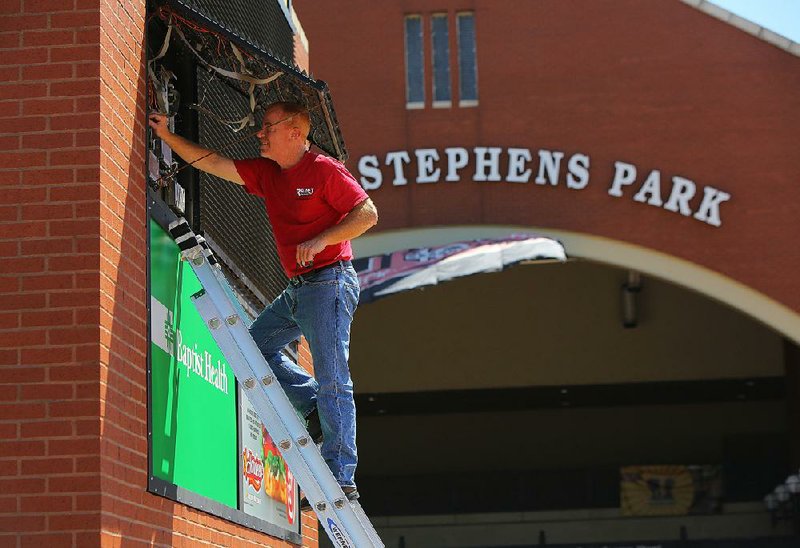 John Engster, a service manager with Rainey Electronics, performs repairs Tuesday to the marquee in front of the home of the Arkansas Travelers at Dickey-Stephens Park in North Little Rock. The Travelers announced Tuesday a new two-year agreement to become the Class AA affiliate of the Seattle Mariners.