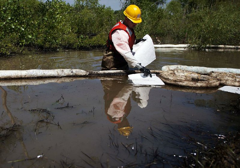 A worker uses oil-absorbent sheets to clean up an Exxon spill in the Yellowstone River in Laurel, Mont., in this July 6, 2011, file photo. 