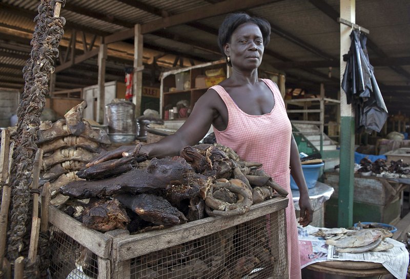 In this file photo taken on Wednesday, Oct. 22, 2014, Yaa Kyarewaa, await clients as she stands next to her makeshift bush meat shop at one of the largest local markets in Accra, Ghana.