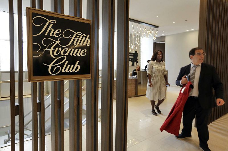 A runner carries a garment through the entrance of the Fifth Avenue Club at the Saks Fifth Avenue flagship store in New York. Luxury goods retailers are adding amenities to help attract shoppers.