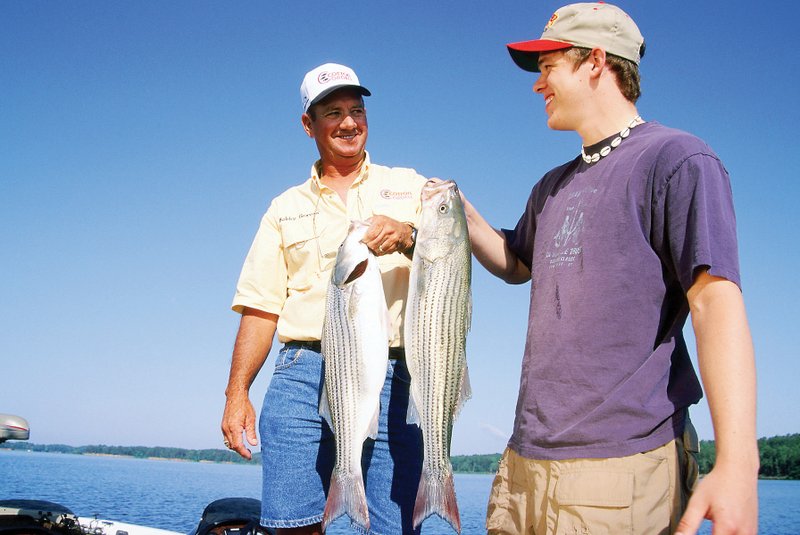 Bobby Graves of Mount Ida, left, and Matt Sutton of Alexander show off a pair of hard-fighting stripers caught in Lake Ouachita.