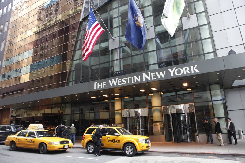 FILE - In this Wednesday, Feb. 1, 2012, file photo, a man hails a taxi in front of the Westin New York hotel, in New York. Marriott International closed early Friday, Sept. 23, 2016, on its acquisition of Starwood Hotels & Resorts Worldwide, bringing together its Marriott, Courtyard and Ritz-Carlton brands with Starwood’s Sheraton, Westin, W and St. Regis properties. (AP Photo/Mark Lennihan, File)
