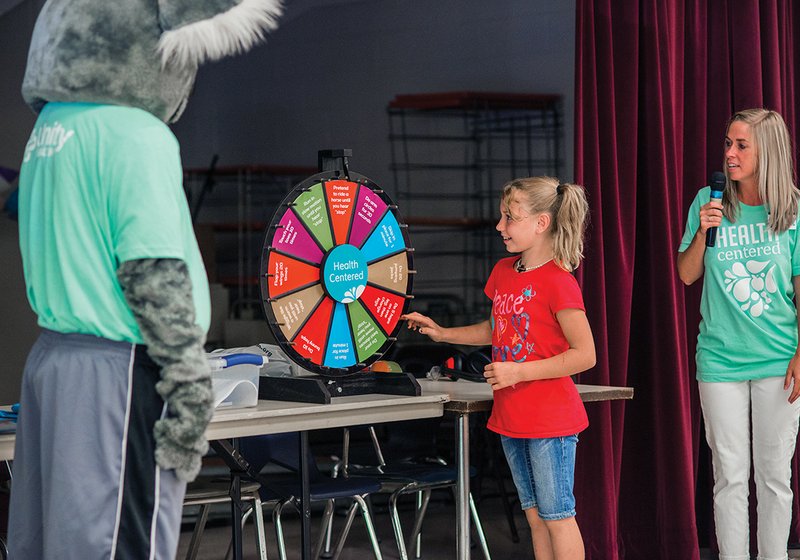 KC Koala, left, the mascot for Unity Health-White County Medical Center, watches as Cassie Williams spins the wheel of exercise. Anna Broomfield, Unity Health marketing coordinator and spokesperson for the Kids Ambassador Program is also shown during a presentation at McRae Elementary School.