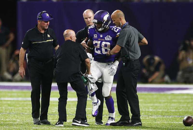 Minnesota Vikings running back Adrian Peterson (28) is helped off the fi eld while Coach Mike Zimmer looks on during the second half of last week’s victory over the Green Bay Packers. Peterson underwent surgery Thursday to repair a torn lateral meniscus in his right knee, and the Vikings placed him on injured reserve with the intent to return this season. Peterson could return to the lineup as soon as Week 11 in November.