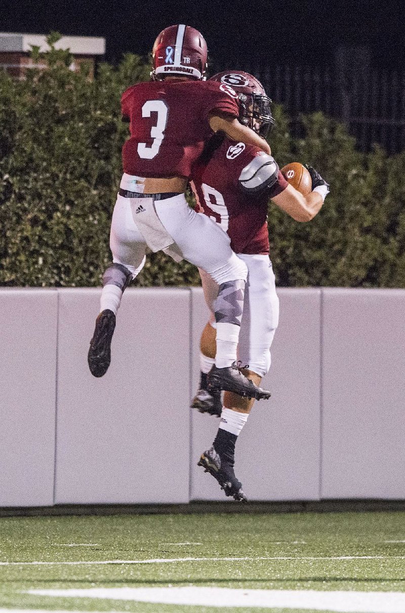 Kyler Williams (3) and Alex Thompson of Springdale celebrate a touchdown in the Bulldogs’ 42-21 victory over Rogers Heritage on Friday in Springdale.