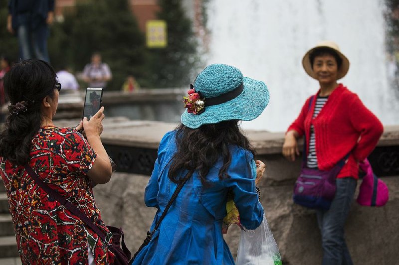 Chinese tourists pose for photos at a fountain just off Red Square in Moscow last month. Spending by Chinese in other nations is growing at a much faster pace than the number of Chinese abroad, a former U.S. Treasury official says.