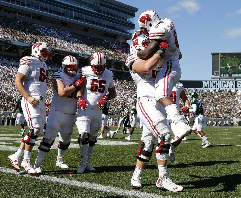 Wisconsin running back Corey Clement (left) is lifted in the air by offensive lineman Beau Benzschawel as other teammates look on Saturday to celebrate a touchdown during the third quarter of the No. 11 Badgers’ 30-6 victory over No. 8 Michigan State in East Lansing, Mich.