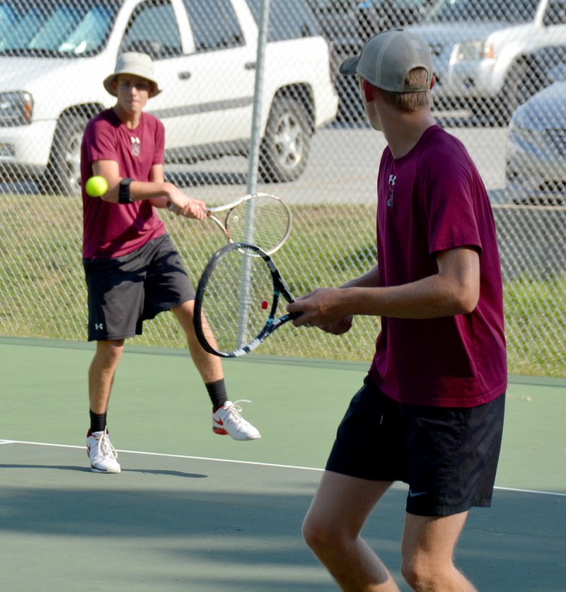 Graham Thomas/Siloam Sunday Siloam Springs senior tennis player Kip Dooley, left, makes a play on the ball as doubles partner Noah Slater looks on Tuesday during the Panthers&#8217; match against Greenwood at the John Brown University tennis courts.