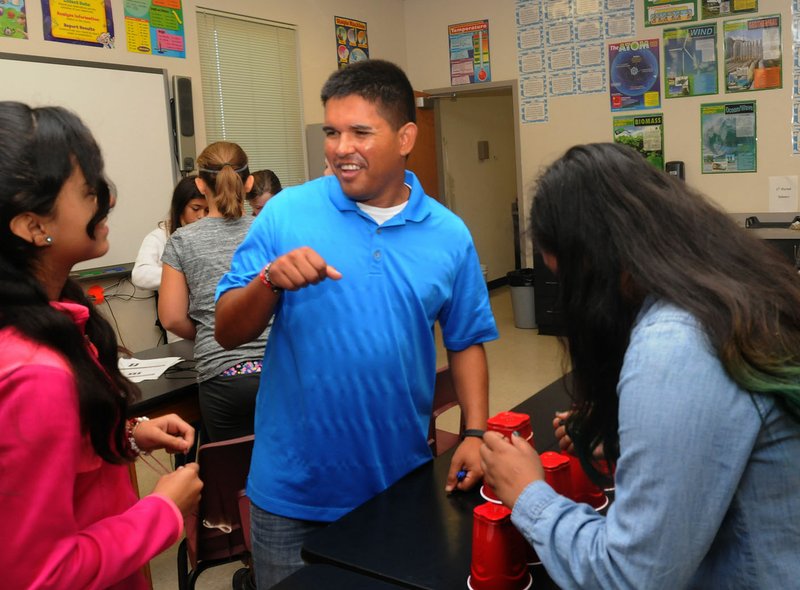 Ryan Quintana, world history and science teacher at Lingle Middle School in Rogers, works Friday with students on a science project. Quintana qualified for a one-time bonus of $5,000 this past spring. It’s paid to Hispanic teachers and administrators once they’ve completed five years with the district.