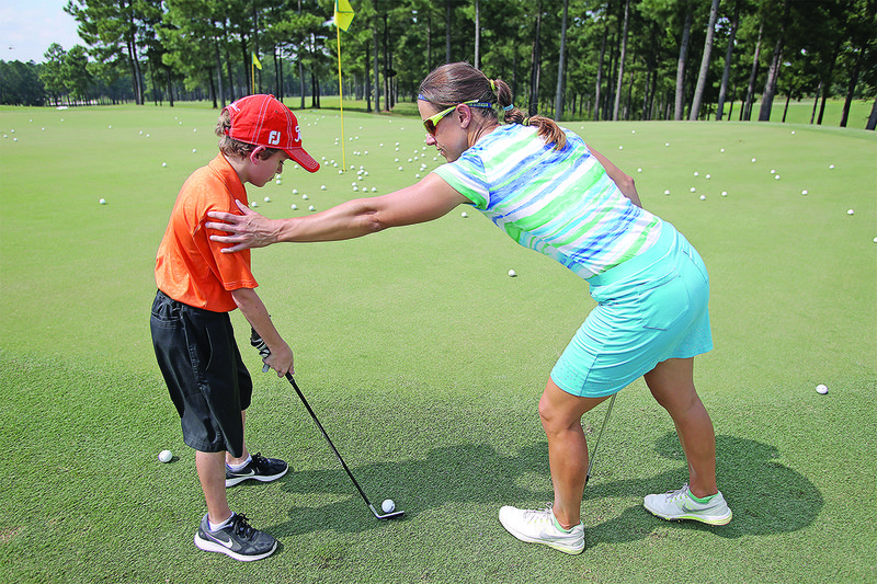 Symetra Tour professional Alexandra Casi works with Joshua Lee on his chipping skills during the Murphy USA El Dorado Shootout Jr. golf clinic at Mystic Creek Golf Course on Sunday.