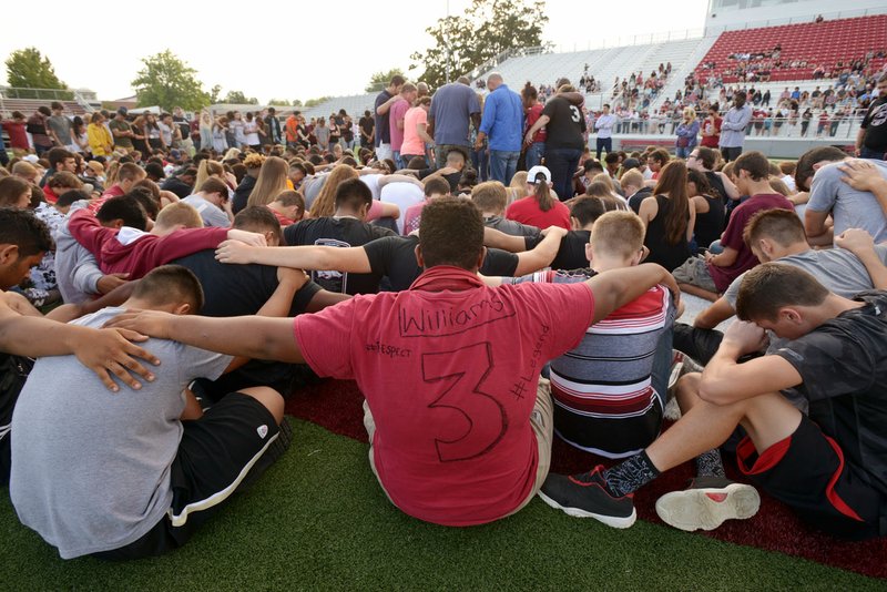 Joseph Briand-Carter (center), a Springdale sophomore football player, wears a shirt decorated in memory of his teammate Kyler Williams on Sunday as students surround Williams’ family in support during a gathering at Jarrell Williams Bulldog Stadium in Springdale to honor Williams, a wide receiver at Springdale who died overnight in a single-vehicle crash.