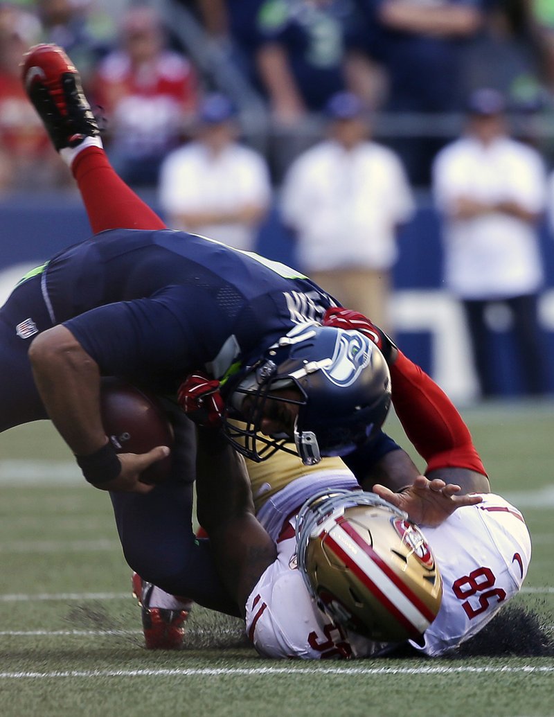 Seattle Seahawks quarterback Russell Wilson, top, is pulled down by San Francisco 49ers' Eli Harold in the second half of an NFL football game, Sunday, Sept. 25, 2016, in Seattle. (AP Photo/Ted S. Warren)