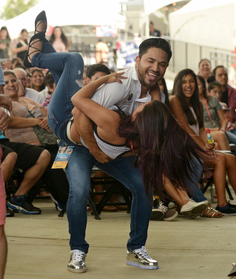 Hugo Real, a host for Univision Arkansas, dips Estrella Ordonez of Rogers Sunday while Banda La Poderosa performs during the third annual Celebrando La Musica Presentado Por Wal-Mart at the Wal-Mart Arkansas Music Pavilion in Rogers.