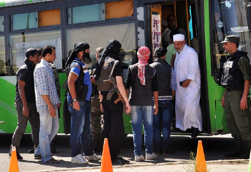 Syrian rebel fighters board a bus Monday as they leave the besieged rebel-held neighborhood of al-Waer in the city of Homs.