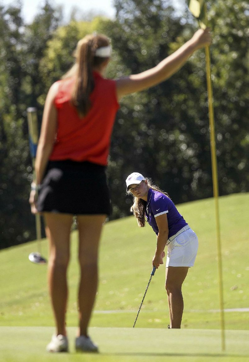 Bailey Dunstan (back) of Baptist Prep chips onto the green while Lilly Thomas of Heber Springs holds on to the flag stick during the Class 4A girls state golf tournament at Maumelle Country Club on Tuesday. Dunstan shot a 3-over 76 Tuesday, finishing second to her sister Kaitlyn, but she helped Baptist Prep win the team title over Central Arkansas Christian by 24 shots. She also advanced to the Overall tournament at Pleasant Valley Country
Club in Little Rock on Oct. 13.