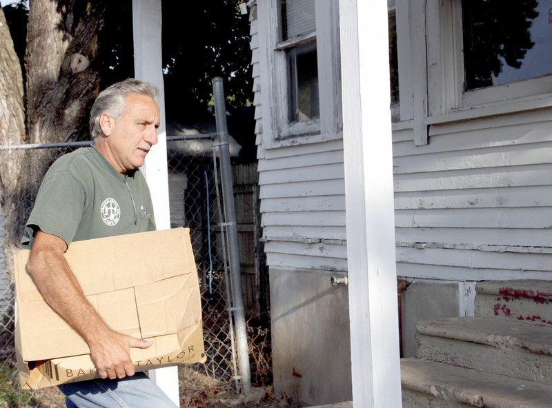 LYNN KUTTER ENTERPRISE-LEADER Ron Corey with the city of Prairie Grove moves boxes of books into the former Skelton House on Buchanan Street. Friends of Prairie Grove Library will use the building as a used book store.