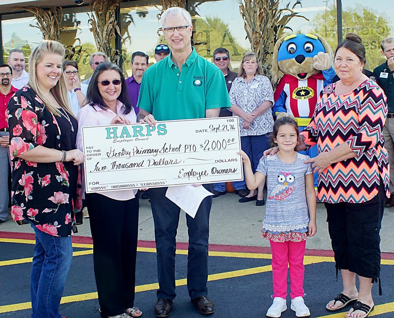 Photo by Randy Moll Jessica Summers, PTO president, Gayla Wilmoth, elementary school principal, Trinity Jacks, elementary school student, and Linda Johnson, high school office aide and great-grandmother to Trinity, receive a $2,000 check for the Gentry Primary School PTO from Roger Collins, Harps CEO, at the new Gentry Harps Food Store on Wednesday, Sept. 21, 2016.