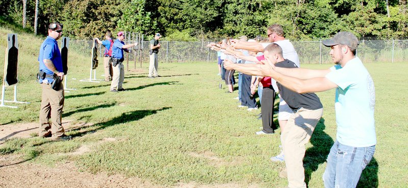 Keith Bryant/The Weekly Vista Corporal J.D Jordan, left, sergeant Eric Palmer and sergeant Scott Vanetta coach the citizen police academy students on proper firing stances at the Bella Vista POA gun range.