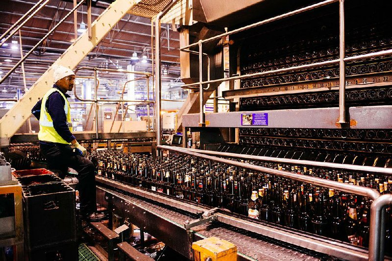 A worker watches as used beer bottles pass through a recycling machine at SABMiller Plc’s Newlands brewery in Cape Town, South Africa, in this file photo. SABMiller and Anheuser-Busch InBev shareholders on Wednesday approved Anheuser-Busch’s takeover deal valued at more than $100 billion. 